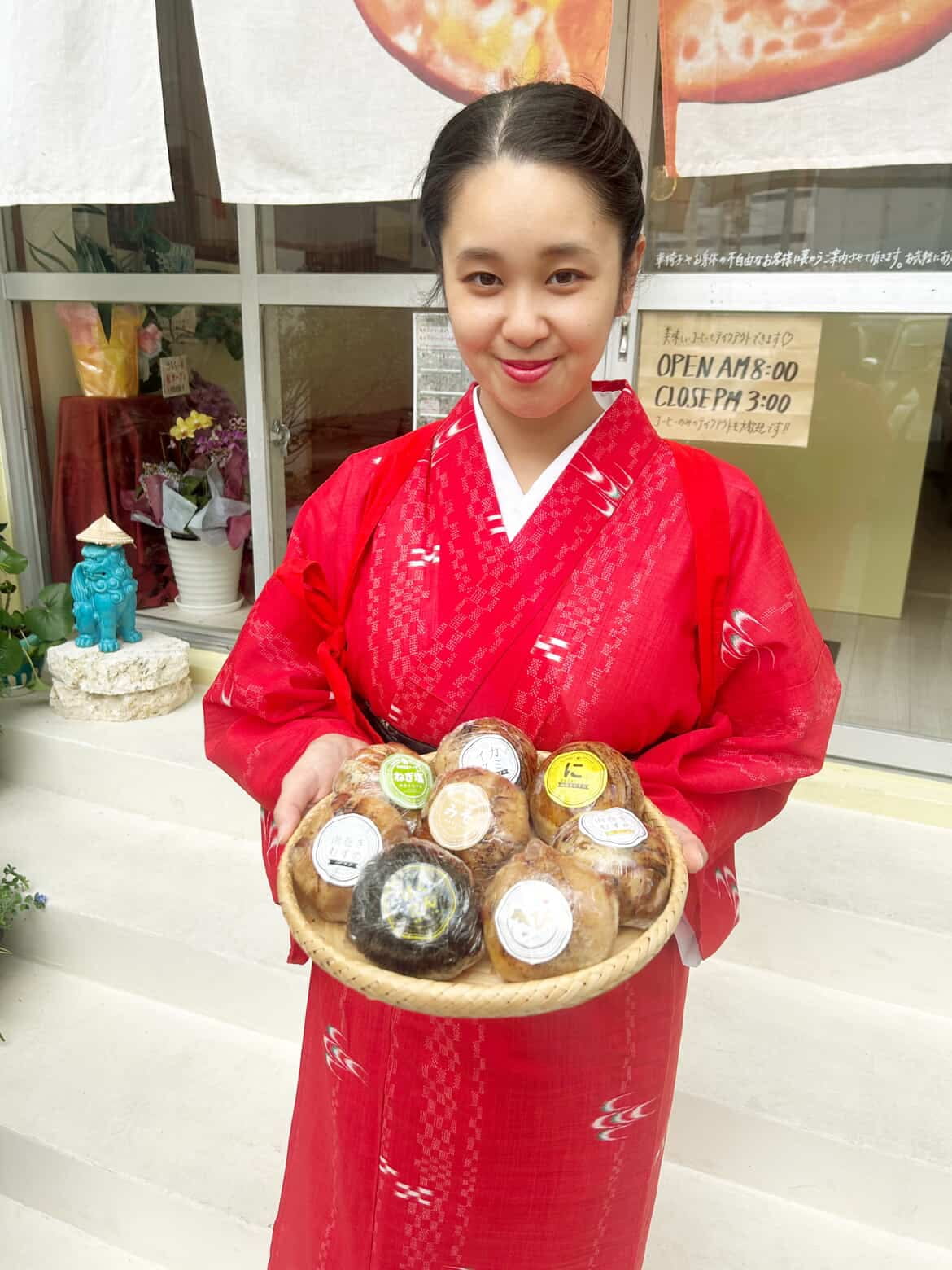 赤い着物姿で肉巻きおにぎりを持つスタッフ